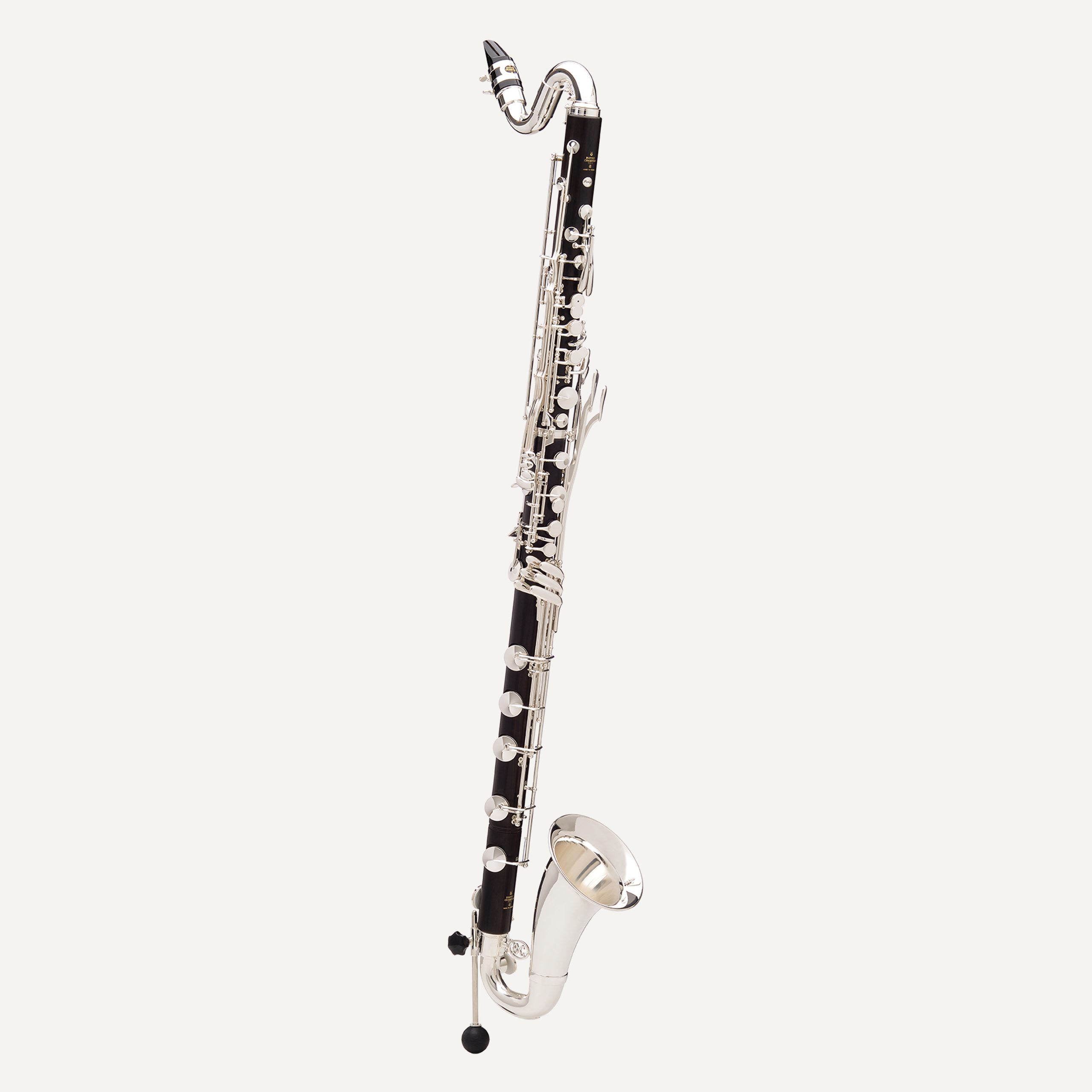 The Buffet Prestige Low C Bass Clarinet, featuring silver keys and a curved neck and bell, stands upright against a plain light background.