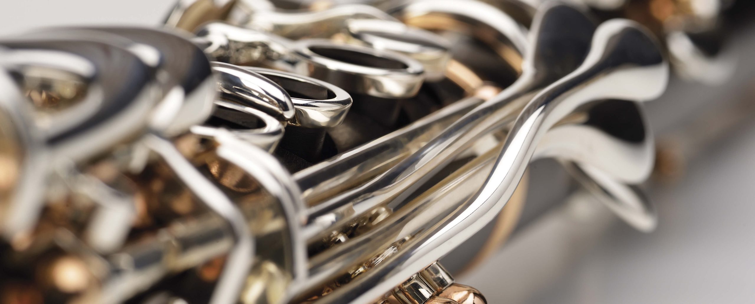 Close-up view of the shiny metal keys and intricate mechanisms of a woodwind instrument, possibly a clarinet or saxophone, highlighting the craftsmanship that often influences clarinet price.